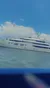 A large, luxurious yacht is sailing on the ocean beneath a clear blue sky with fluffy clouds.