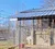 A white animal is inside a fenced enclosure with a covered roof, and a red object is on the ground.