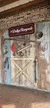 A rustic wooden wall features a collection of old tools and a sign reading 