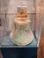 The image shows a weathered ship's bell encased in a display with information about its origin and location.