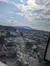 The image shows an aerial view of an amusement area with rides, buildings, a parking lot, and mountains in the background under a partly cloudy sky.