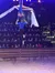 Two aerial performers are executing a routine with silk fabrics above an audience in an arena.