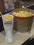 A large cup with a frozen drink and a bucket of popcorn are sitting on a counter.