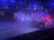 Riders on horseback parade with American flags in a dimly lit arena.
