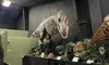 A large dinosaur exhibit features a Tyrannosaurus rex model in a museum setting, surrounded by other dinosaur figures and plants.