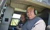 Two people wearing headsets are sitting inside a helicopter.