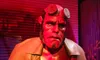 A figure resembling a red-skinned character with horn stubs and a trench coat stands against a shadowy backdrop.