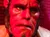 A figure resembling a red-skinned character with horn stubs and a trench coat stands against a shadowy backdrop.