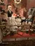 The image shows a vintage-themed window display featuring mannequins dressed in historical children's clothing, a carousel horse, and various period accessories.