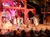 A group of people is performing a lively stage show with a rustic barn and treehouse set, while an audience in cowboy hats watches.