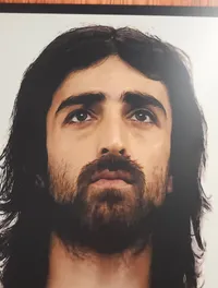 A portrait of a person with long hair and a beard, looking upward, is displayed in a wooden frame.