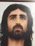 A portrait of a person with long hair and a beard, looking upward, is displayed in a wooden frame.