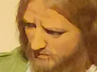 A group of figures resembling a scene from the Last Supper is displayed behind silhouetted foliage.