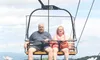 A man and a woman are sitting on a ski lift at SkyLand Ranch, surrounded by a backdrop of mountains and daisies with the text 