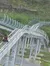 A person is riding a single-seat roller coaster cart on a track winding through a hilly, green landscape.