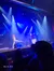 A lively stage performance with two performers in front of an audience, under colorful spotlights.