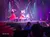 A lively stage performance featuring dancers in red skirts twirling under bright lights with an audience watching.