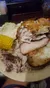 The image shows a plate of food containing roasted chicken, a baked potato, a piece of corn on the cob, and a biscuit.