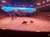 The image shows an indoor arena with a sandy floor, where horses and performers in colorful costumes are part of a dramatic show staged against a scenic mountain backdrop.