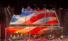 A performer is on stage at the Grand Ole Opry, with a vibrant backdrop featuring the American flag and a sunset.