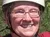 A group of people wearing helmets and harnesses are gathered on a wooden platform, smiling and posing for the photo, likely before ziplining in a forested area.