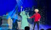 A theater performance features a person dressed as the Statue of Liberty and another in a red shirt and fur hat, set against a cityscape backdrop with dramatic lighting.