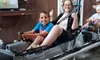 A child and an adult are sitting in a bobsled ride cart, smiling and giving thumbs up.