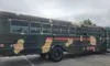 The image shows a bus painted in a camo pattern with the text 