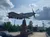 A vintage fighter plane sculpture mounted on a brick pedestal with a partly cloudy sky in the background.