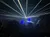 A crowd watches a vibrant laser light show in a darkened venue.