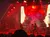 A musician playing the violin performs energetically on stage with fiery visuals and dramatic lighting.