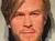 A wax statue of a man with blond hair, wearing a black vest, white shirt, and black pants, stands against a wall with a height chart.
