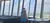 A couple is standing near large windows in a tower, enjoying a panoramic view.