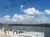 A sunny day on a riverboat with people sitting on deck chairs, overlooking a scenic landscape and string lights above.