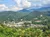 A scenic view of a town nestled in a lush, mountainous landscape under a partly cloudy sky.