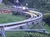 A person is riding a small roller coaster or alpine slide along a curvy track in a lush, green outdoor setting.