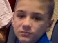 The image shows a large group of people seated in a theater-like setting, with several individuals smiling at the camera.