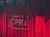 The image shows the stage of the Grand Ole Opry with red curtains and the venue's logo projected onto them.