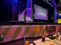 The image shows a dining table set with drinks and food inside a theater, with the 