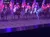 A group of performers on horseback, dressed in illuminated outfits, carry American flags in an arena with an audience.