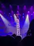 A performer balances on a stack of chairs on a stage illuminated by purple lights.