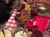 A table is set with a variety of Southern comfort foods, including fried chicken, cornbread, coleslaw, mashed potatoes, a drink in a mason jar, and a bowl of corn, all arranged on a red and white checkered tablecloth.