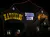 The image shows a building decorated with colorful lights featuring a sign that says