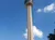 The image shows the Tower of the Americas against a clear blue sky with a few clouds.