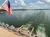 A boat with an American flag is cruising on a calm body of water under a partly cloudy sky.