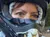 A person wearing a helmet is taking a selfie during an ATV ride with a group of people on a dirt path in a wooded area.