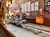 The image shows a row of alpine coaster carts lined up in a wooden shelter, decorated with autumn-themed items and instructional signs.