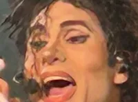 A performer in a gold and black outfit energetically sings on stage with band members playing instruments behind them.
