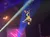 A person is performing upside down with a guitar above a crowd at an indoor event.