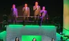 A group of three women in teal gowns sing on stage, with four men in suits performing above them, set against a green-lit, starry backdrop.
